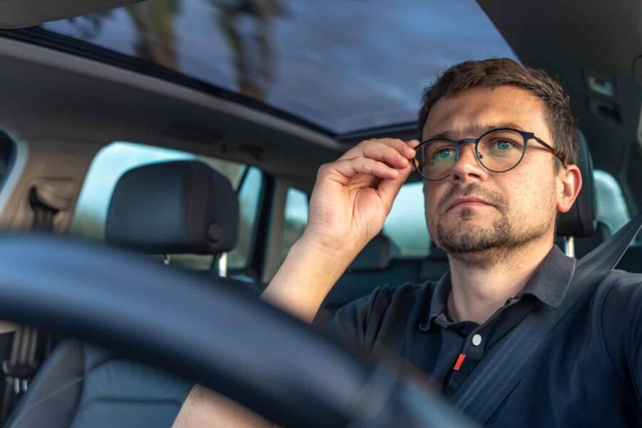 Hommes qui conduite une voiture et porte des lunettes